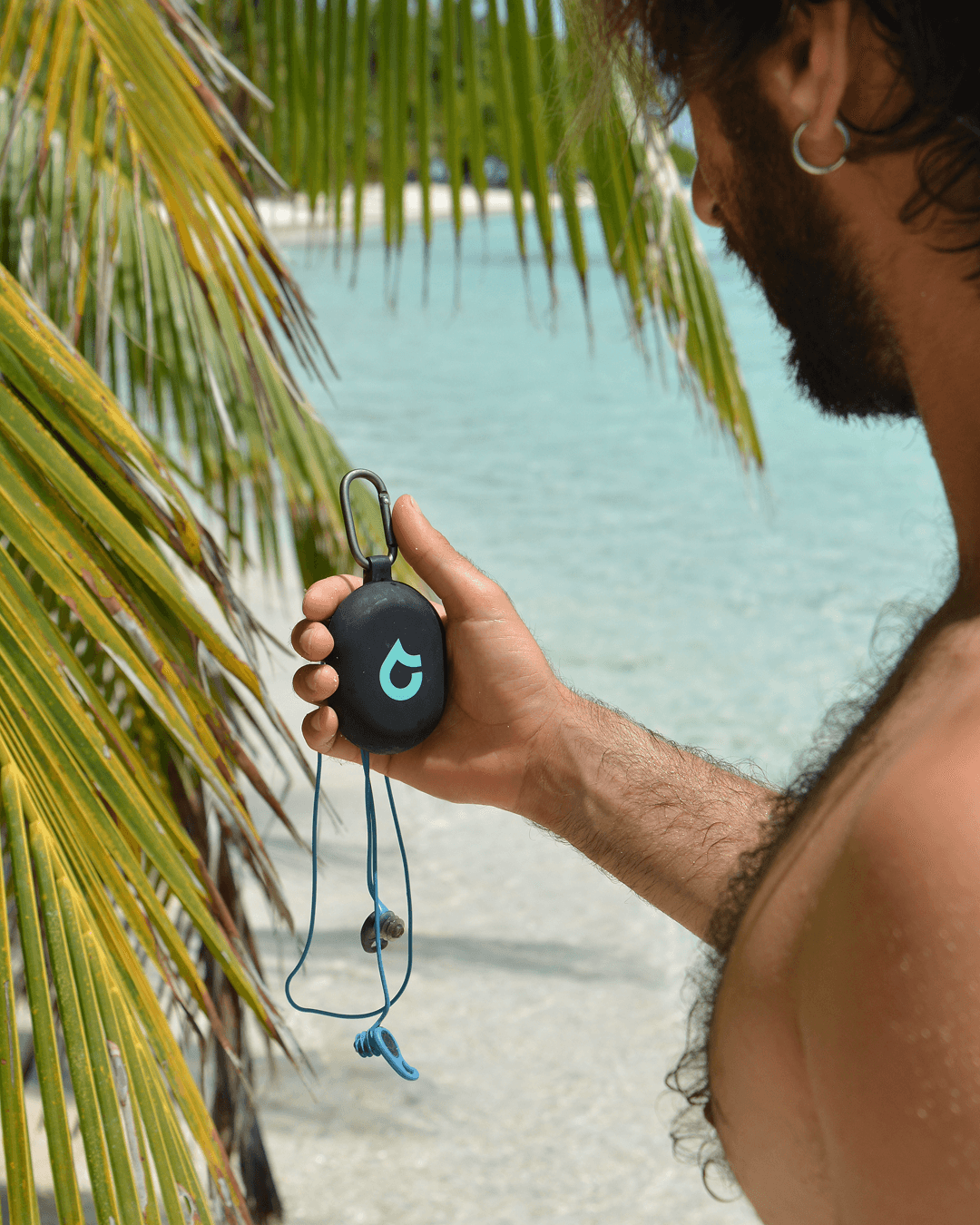 A SEAR Plugs case held up in front of a tropical lagoon